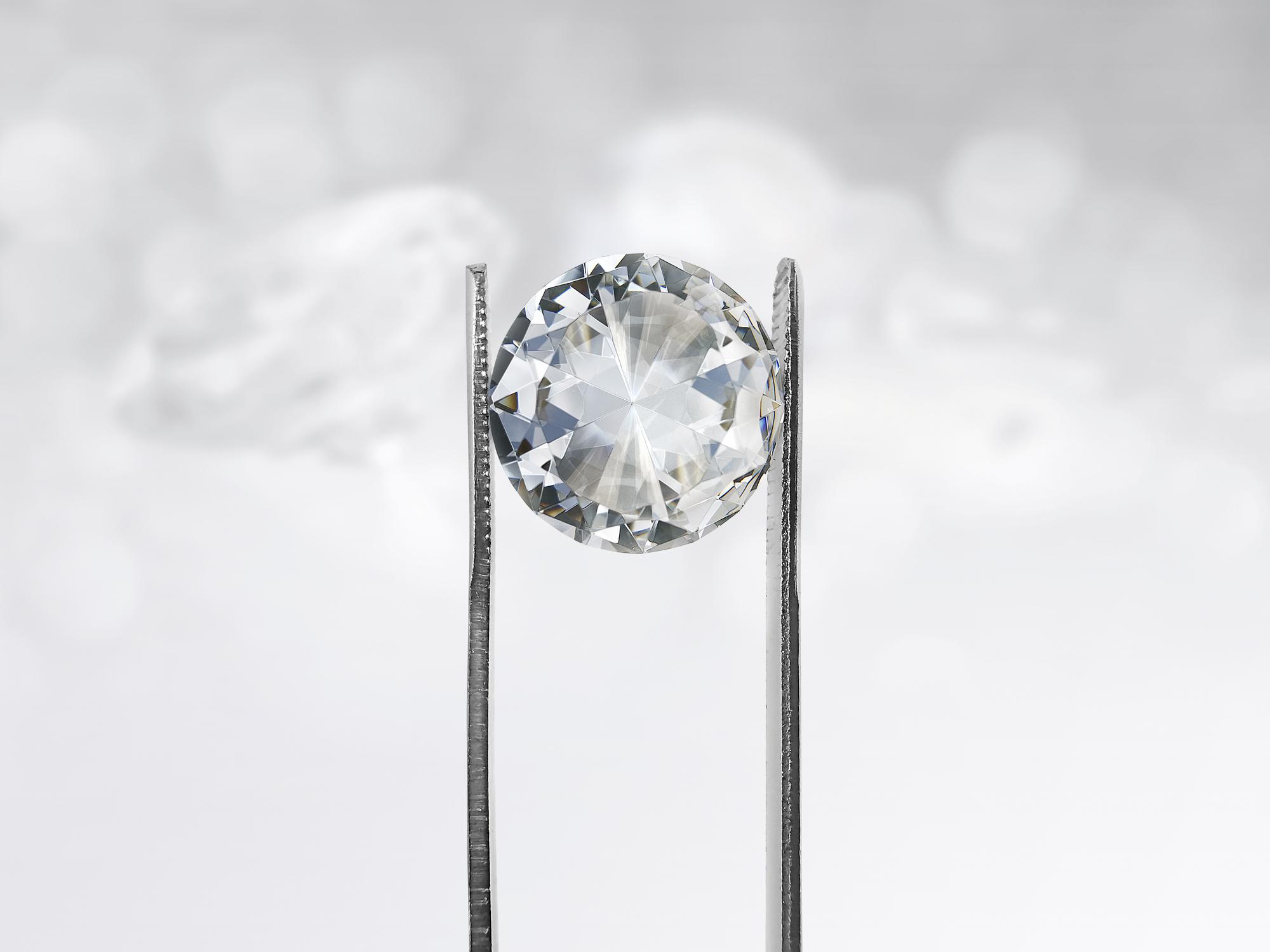 Diamond being held in tweezers being appraised by a diamond buyer